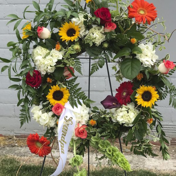 This Sunflower Garden Sympathy Wreath starts at $350.00 Flowers used in this pieces are subject to substitution based upon availability.